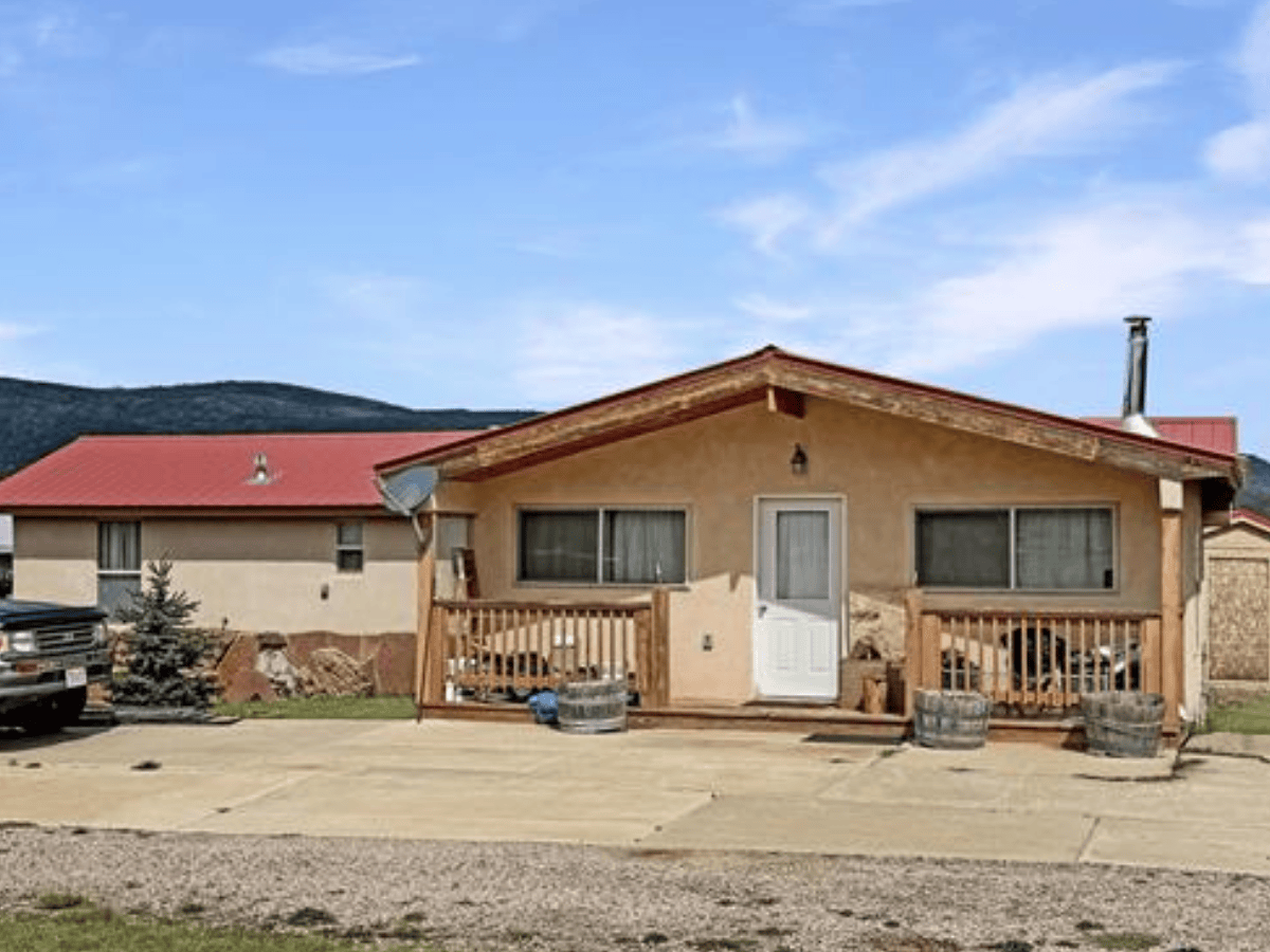 Single-wide manufactured home with a built-on addition and a stucco finished exterior in Angel Fire, NM.