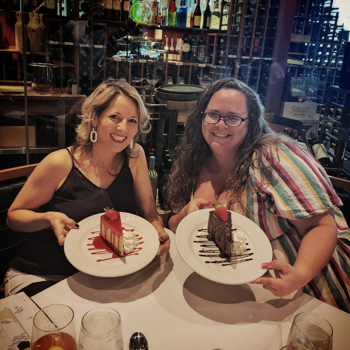 AMA Board Members show off Fogo de Chao desserts in recent visit to the restaurant. Amy Vandermark holds a cheesecake garnished with strawberry sauce and Heather Seltzer holds a CHOCOLATE BRIGADEIRO drizzled with chocolate sauce.