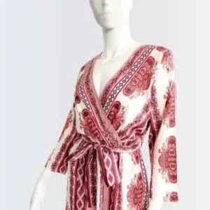 Maniquí vistiendo un jumpsuit largo con estampado bohemio en tonos rosados y vino, escote cruzado en V, manga larga y cinturón ajustable a la cintura. Diseño fluido con aberturas frontales para un estilo libre, cómodo y sofisticado.