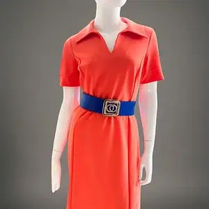 Vestido corto disponible en verde, rosa y coral, con escote en V, cuello abierto estilo polo, mangas cortas y cinturón ajustable, mostrado en maniquí sobre fondo neutro.