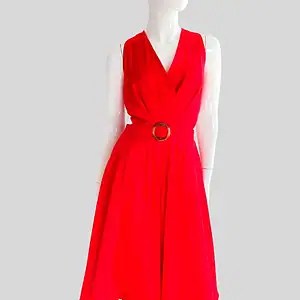 Vestido rojo fucsia sin mangas con escote cruzado, cinturón con hebilla redonda y falda fluida hasta la rodilla, presentado en maniquí sobre fondo gris.