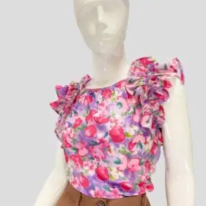 Blusa sin mangas con estampado floral en tonos fucsia, rojo y violeta, vuelos pronunciados en los hombros y corte recto. Combinada con pantalón de vestir marrón. Estilo femenino, alegre y moderno.