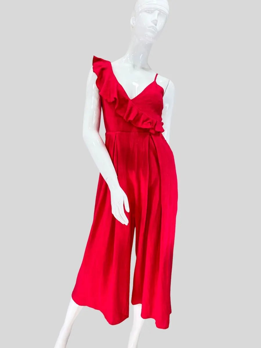 Francisca vistiendo un jumpsuit rojo vibrante con escote cruzado en V y detalle de volantes en un solo hombro. Diseño sin mangas, corte ajustado en la cintura y pantalón fluido estilo culotte para un look sofisticado y femenino. Ideal para eventos especiales o una salida con estilo.
