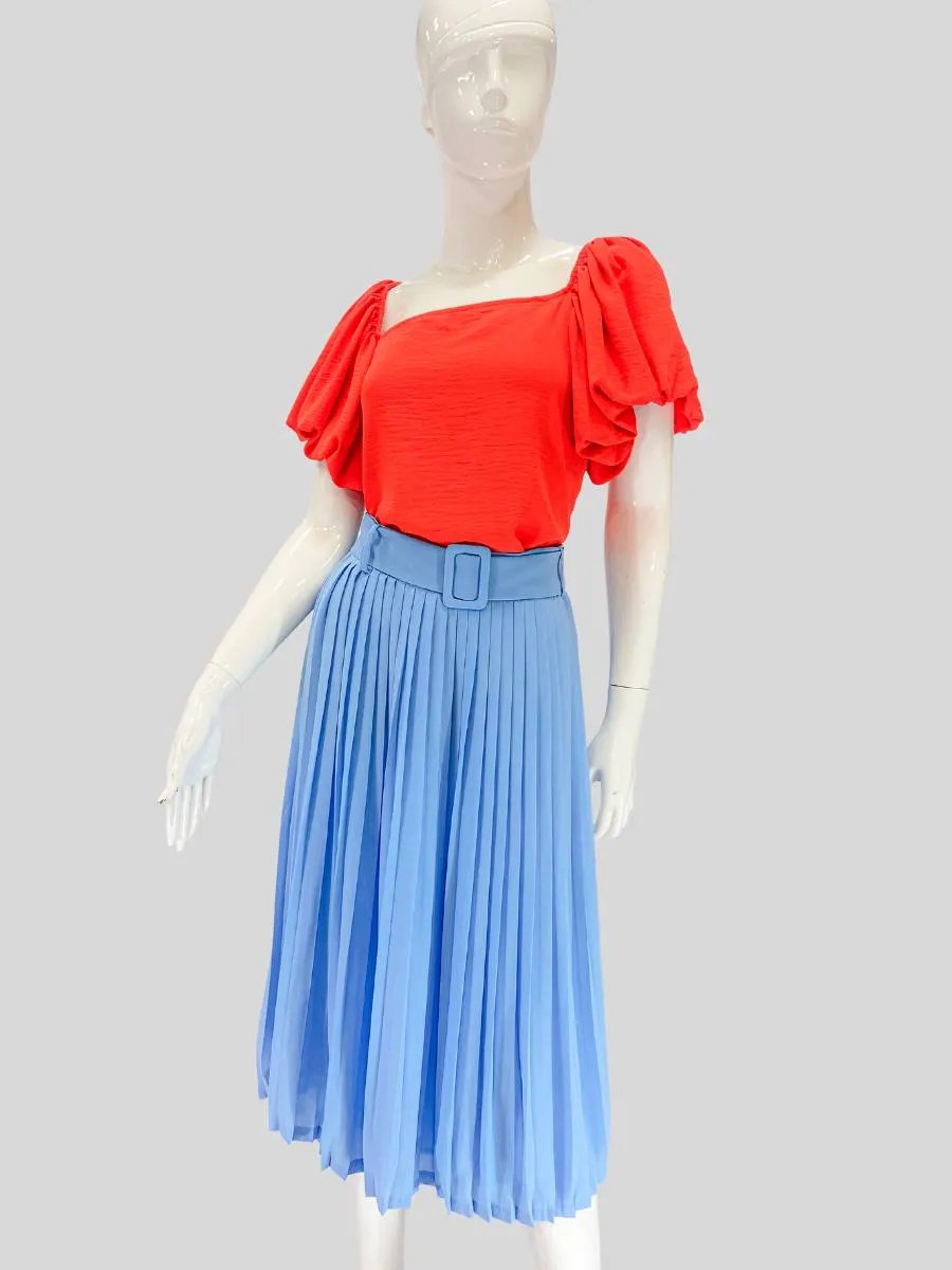 Maniqu con blusa orange y falda plisada azul representando una imagen de empoderamiento femenino a travs de un estilo fresco ordenado y autntico
