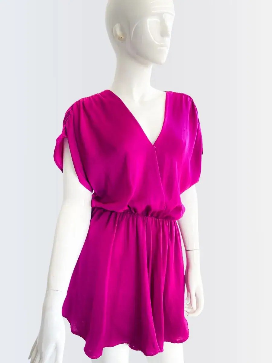 Romper fucsia sin mangas con escote cruzado y corte suelto, modelado por Francisca sobre fondo rosado suave.