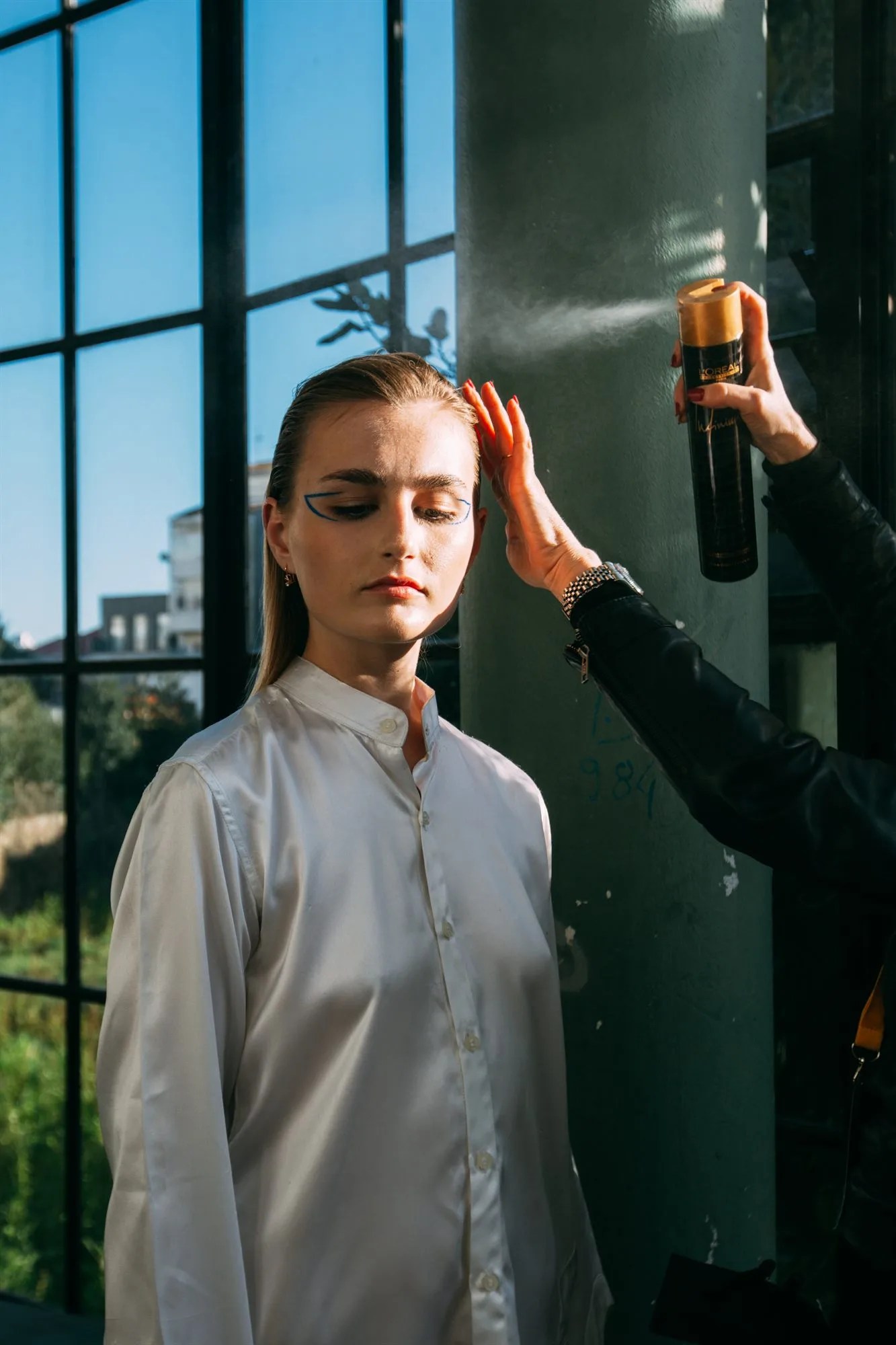 Hair stylist rifinisce l'acconciatura con la lacca