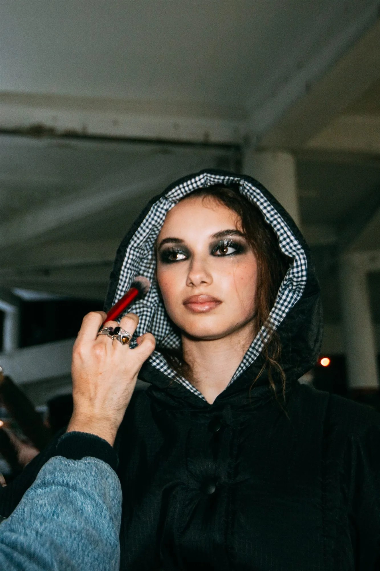 Modella con cappuccio durante i ritocchi nel backstage