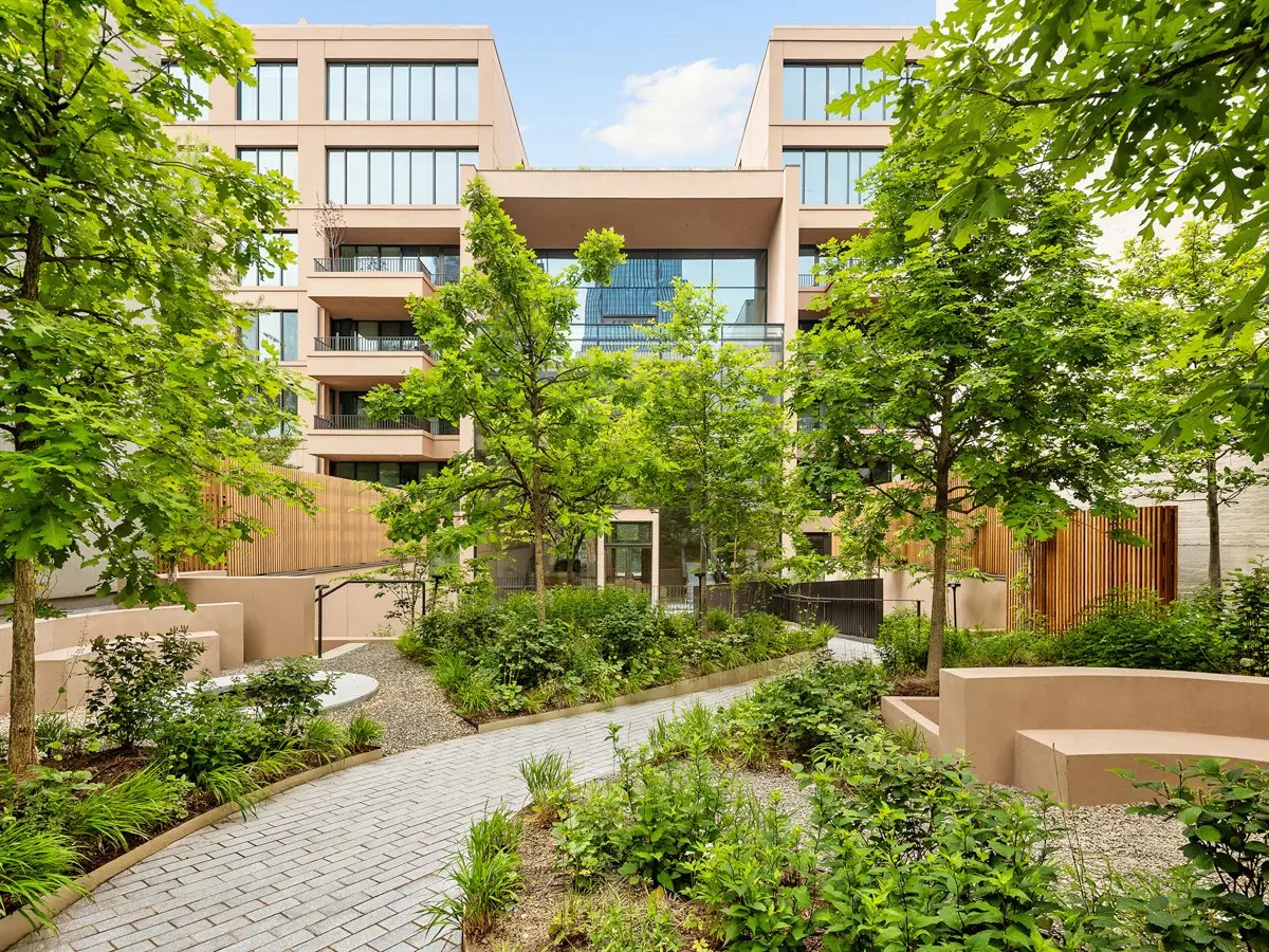 Contemporary residential courtyard with terraced balconies, wood-slat screens, and a stone path through native plantings