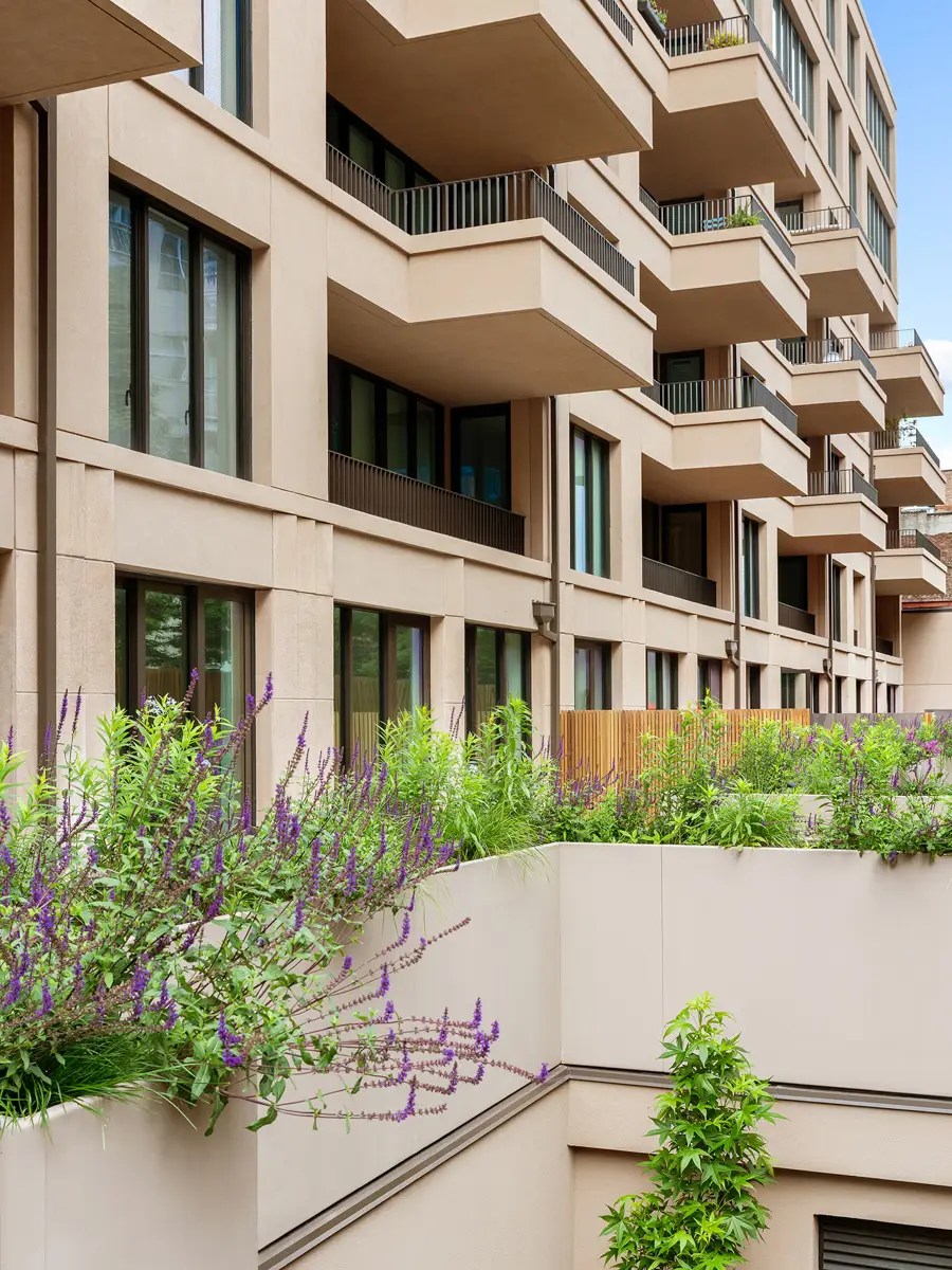 Tiered stone balconies on a residential facade, with flowering salvia spilling over a planter ledge