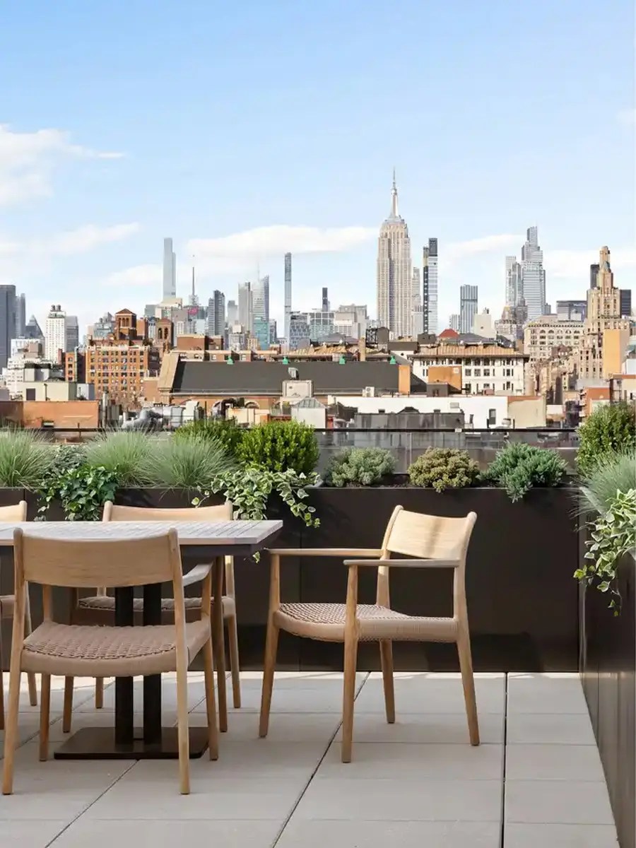 Rooftop dining terrace with woven wood chairs overlooking the Manhattan skyline and Empire State Building