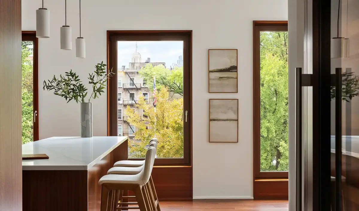 Kitchen island with pendant lights and framed art, windows framing the Empire State Building