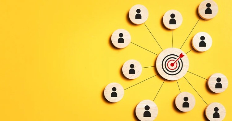 InfluenceMkting_3 • Andrew Roche Wooden icons of people connected to a target with an arrow on a yellow background.