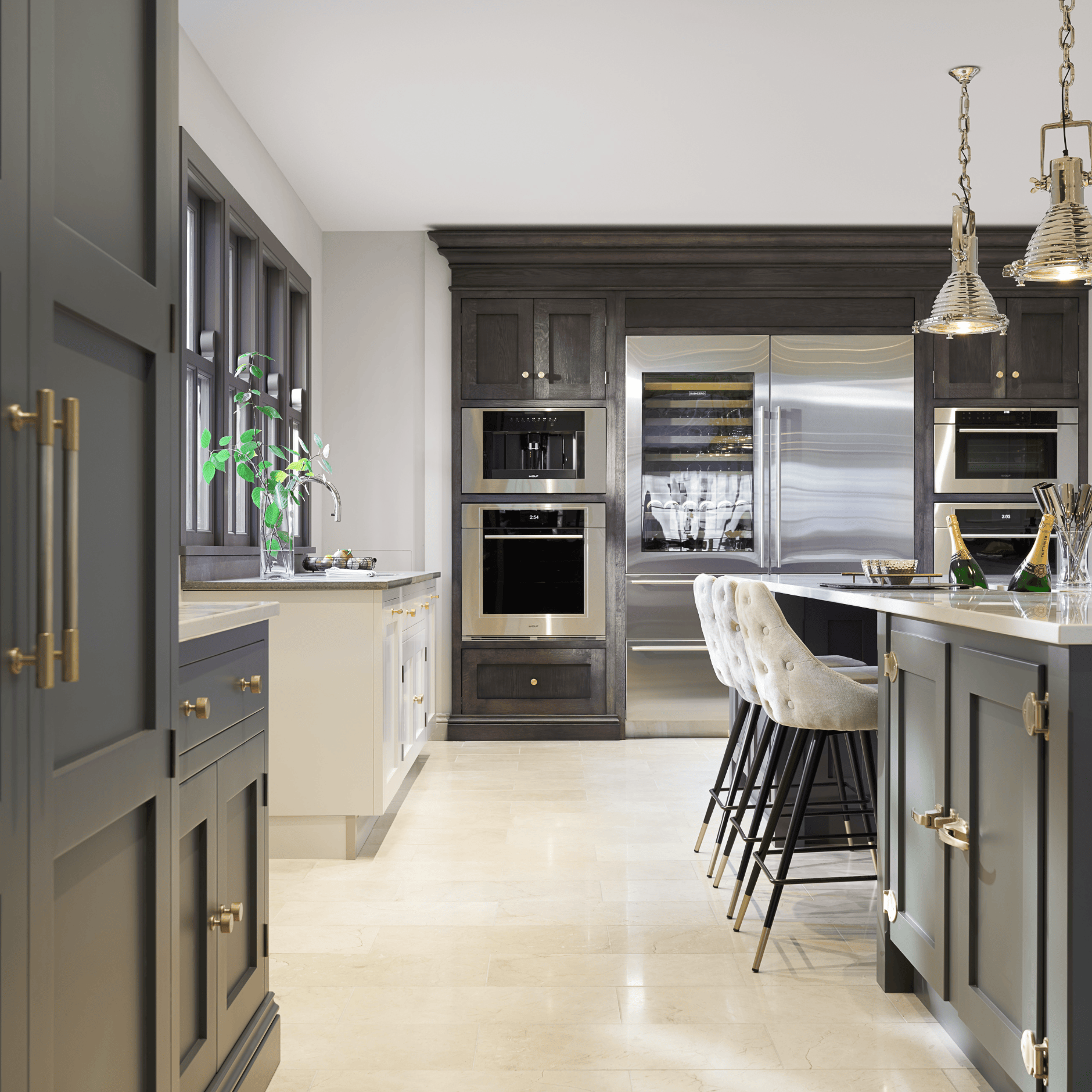 Kitchen with dark cabinetry, integrated steel appliances, a central island with upholstered stools and brass fittings
