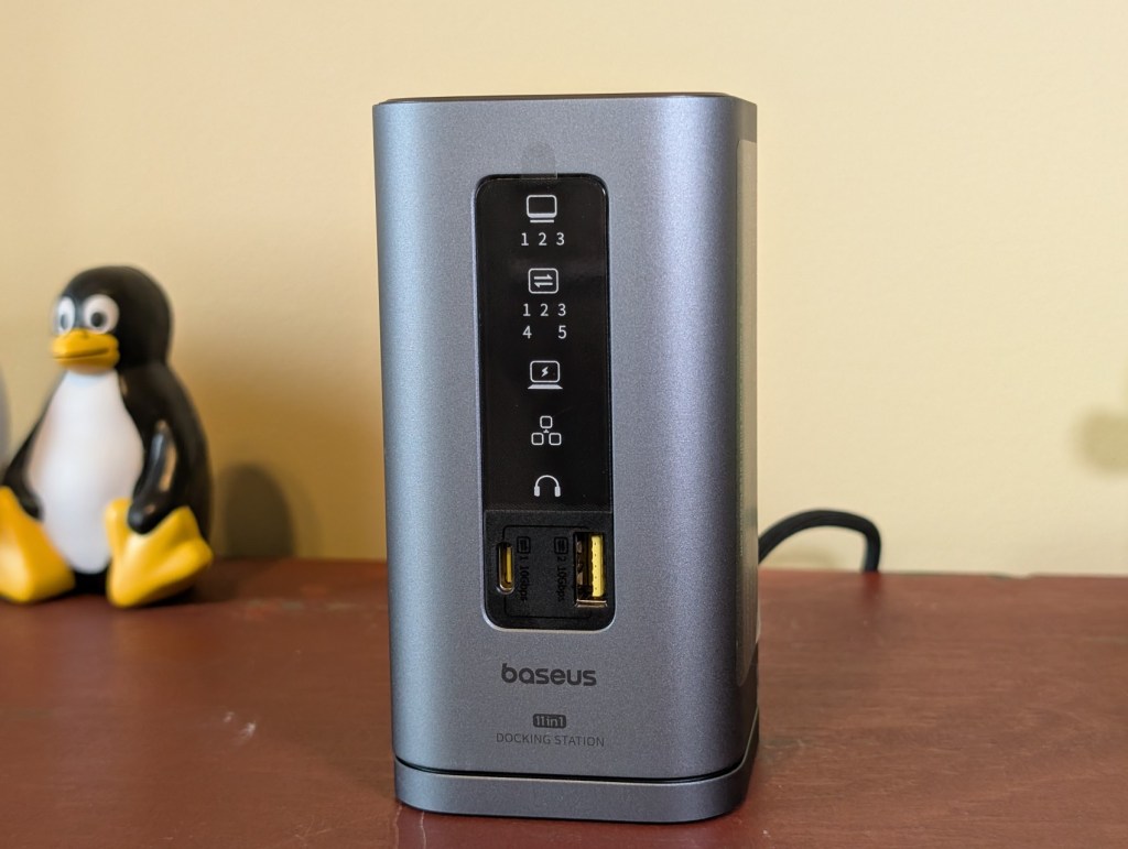 Baseus Spacemate 11-in-1 docking station for Windows featuring front panel LED display and various input/output ports, including USB-C and HDMI, on a desk.