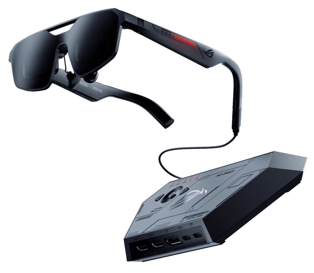 A pair of modern, black smart glasses with dark lenses, labeled ROG XREAL, alongside a sleek, angular black device featuring multiple ports and touch controls.