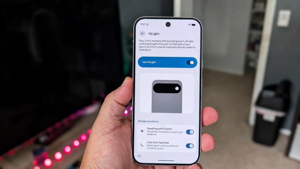 A person holding a smartphone displaying a screen for a feature called HiLight, which uses light and color to inform users of activity. The setup includes options for managing experiences like speaking with Gemini and calls from favorites.