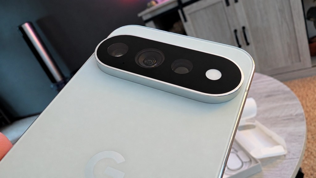 Close-up of a smartphone's camera module, featuring multiple lenses and sensors, with a light-colored back and a slight reflection.