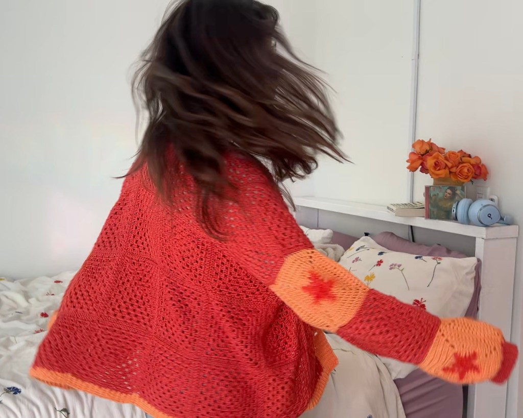 Woman spinning in bright orange crochet cardigan