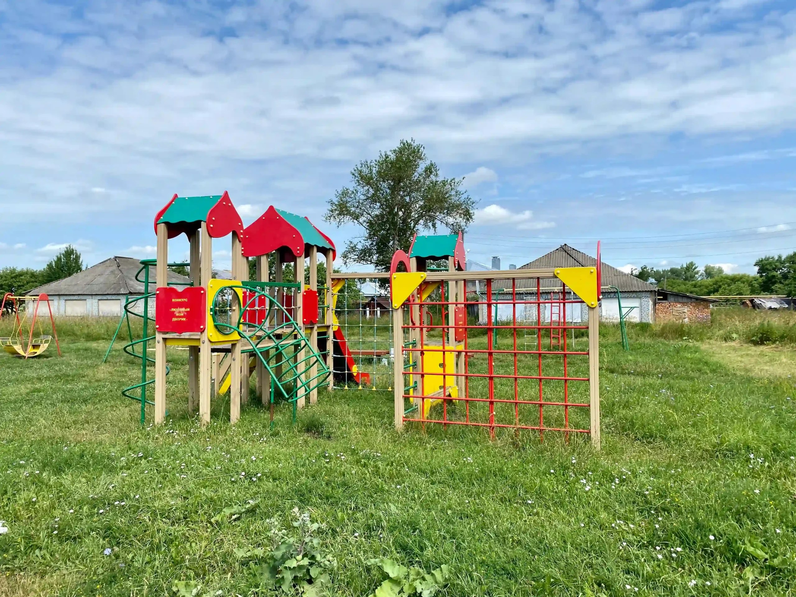 Colorful children’s playground surrounded by grass and village houses