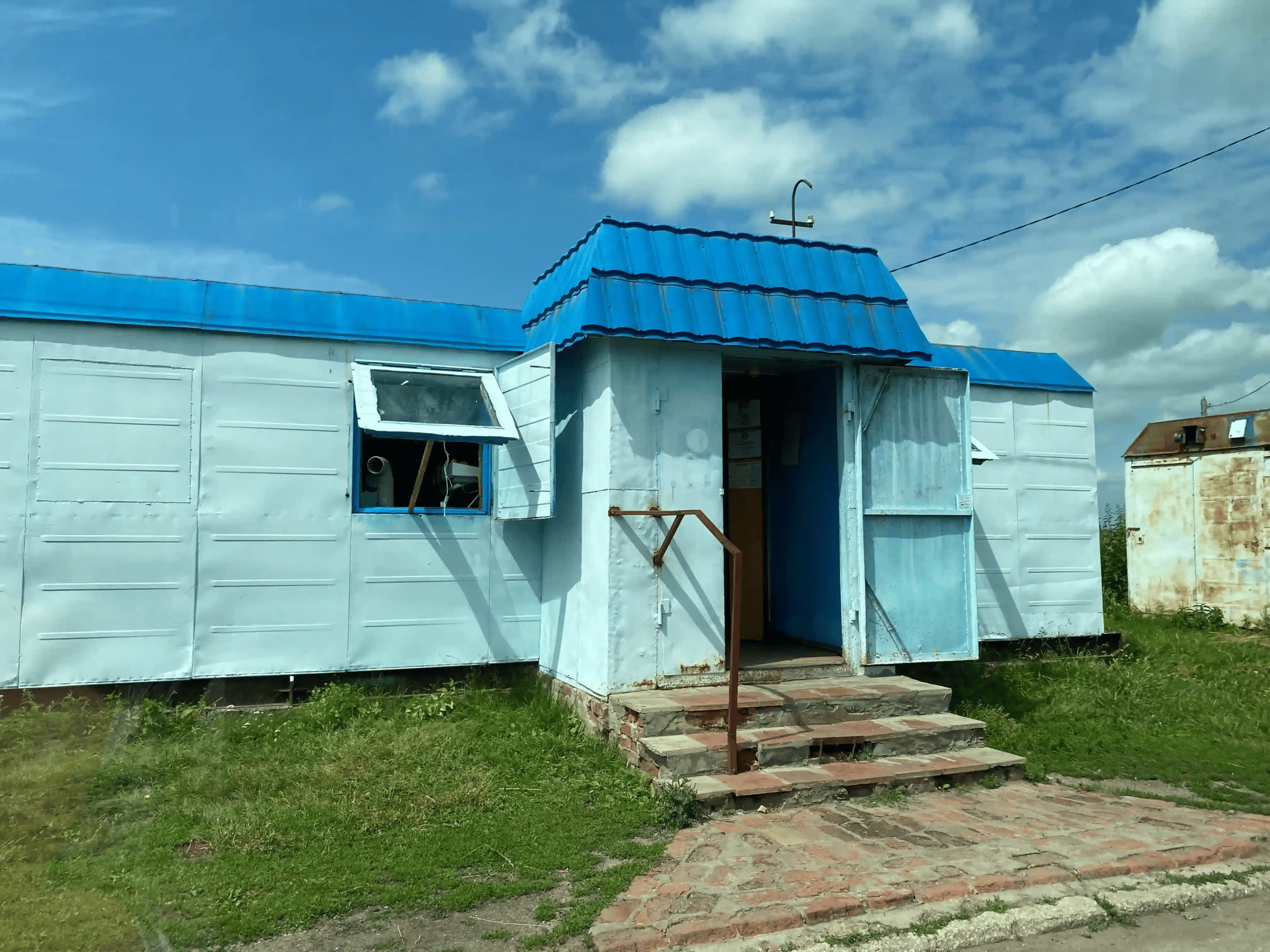 Small metal-sided local shop with a blue roof and open entrance
