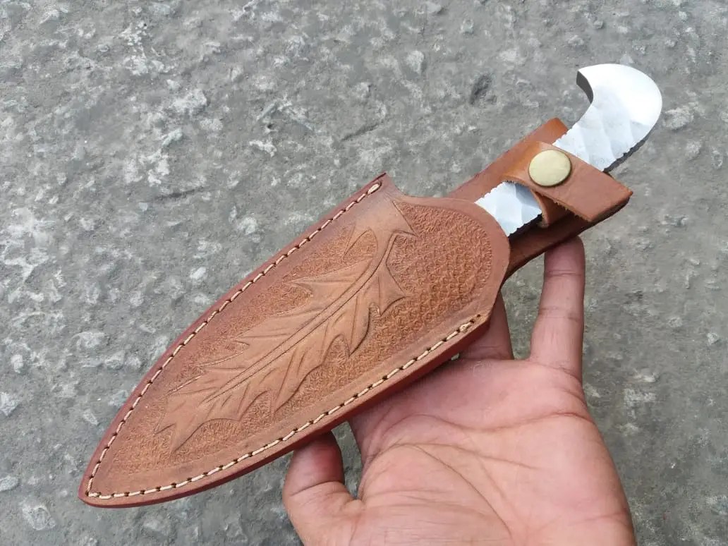 Custom Made 5160 Steel Integral Hunting Knife displayed in its handmade leather sheath, featuring intricate tooling artwork.