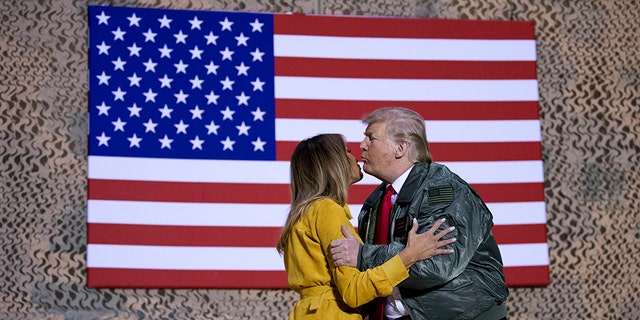 President Donald Trump kisses first lady Melania Trump during a hanger rally at Al Asad Air Base, Iraq, Wednesday, Dec. 26, 2018.
