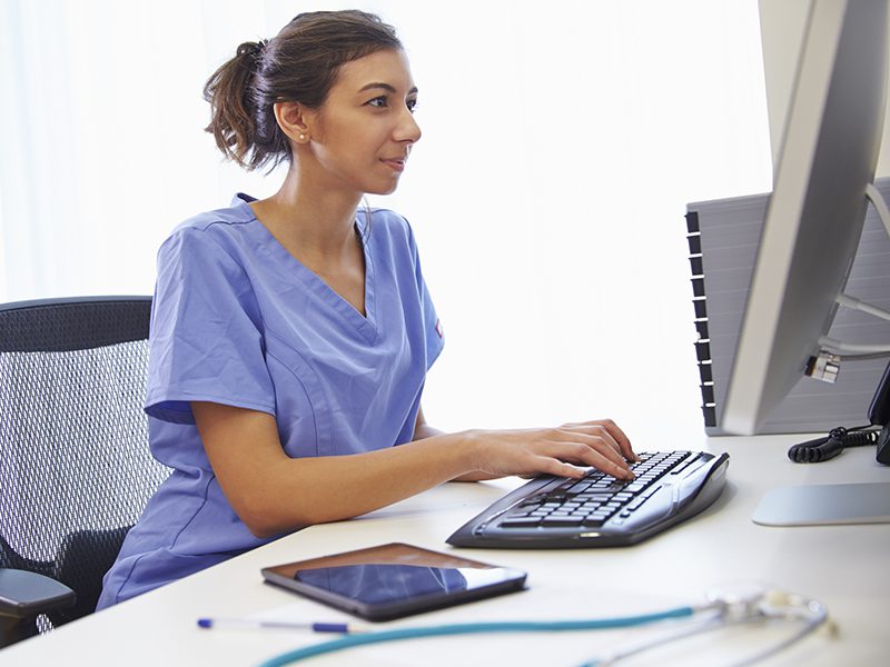 Female Doctor In Office Working At Computer