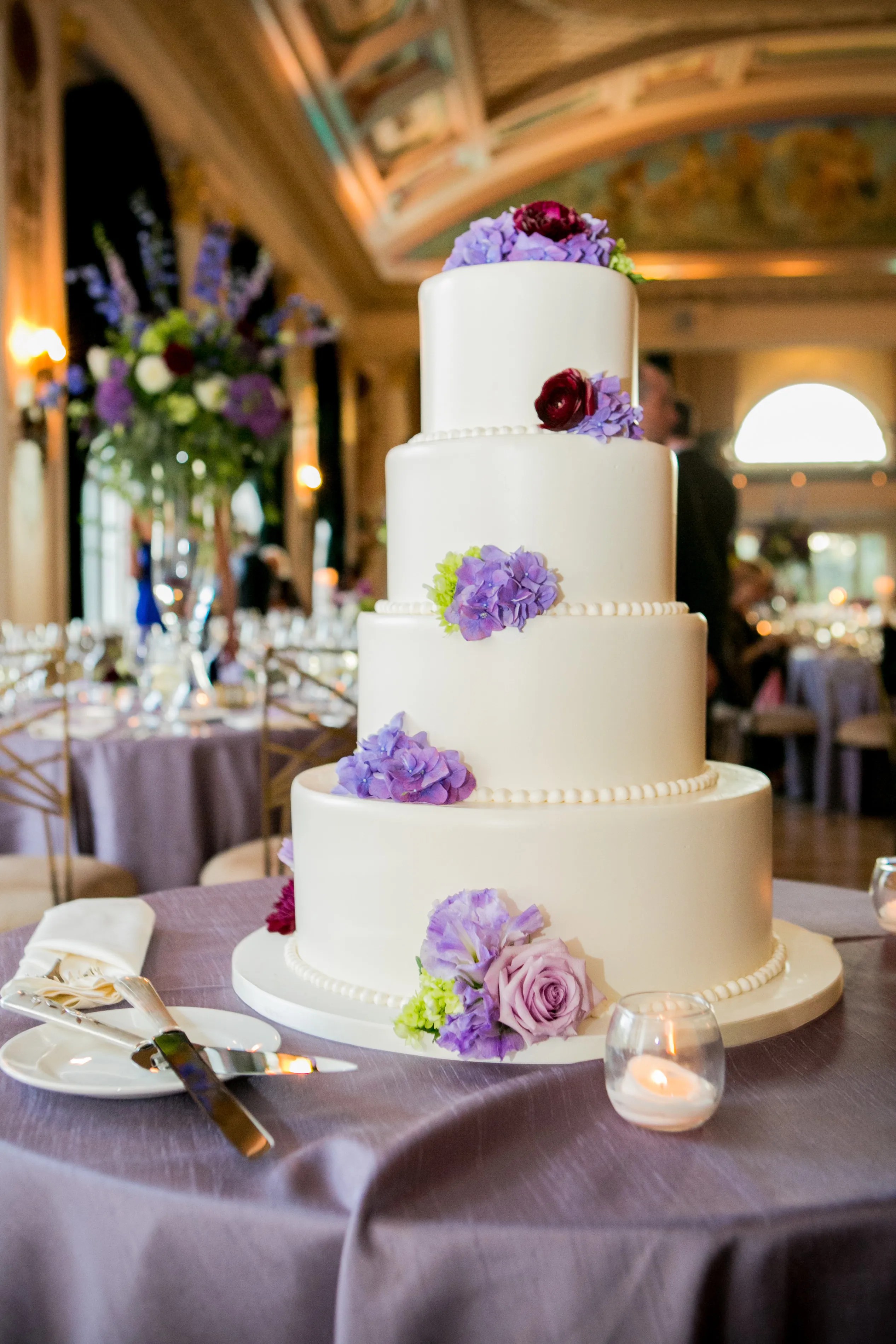 More and more newlyweds are opting to put gifting lounges at their wedding receptions, instead of handing out favors at the ceremony. Four-Tier Wedding Cake With Purple Flowers