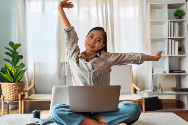 Remote worker stretching at her desk while working from home.