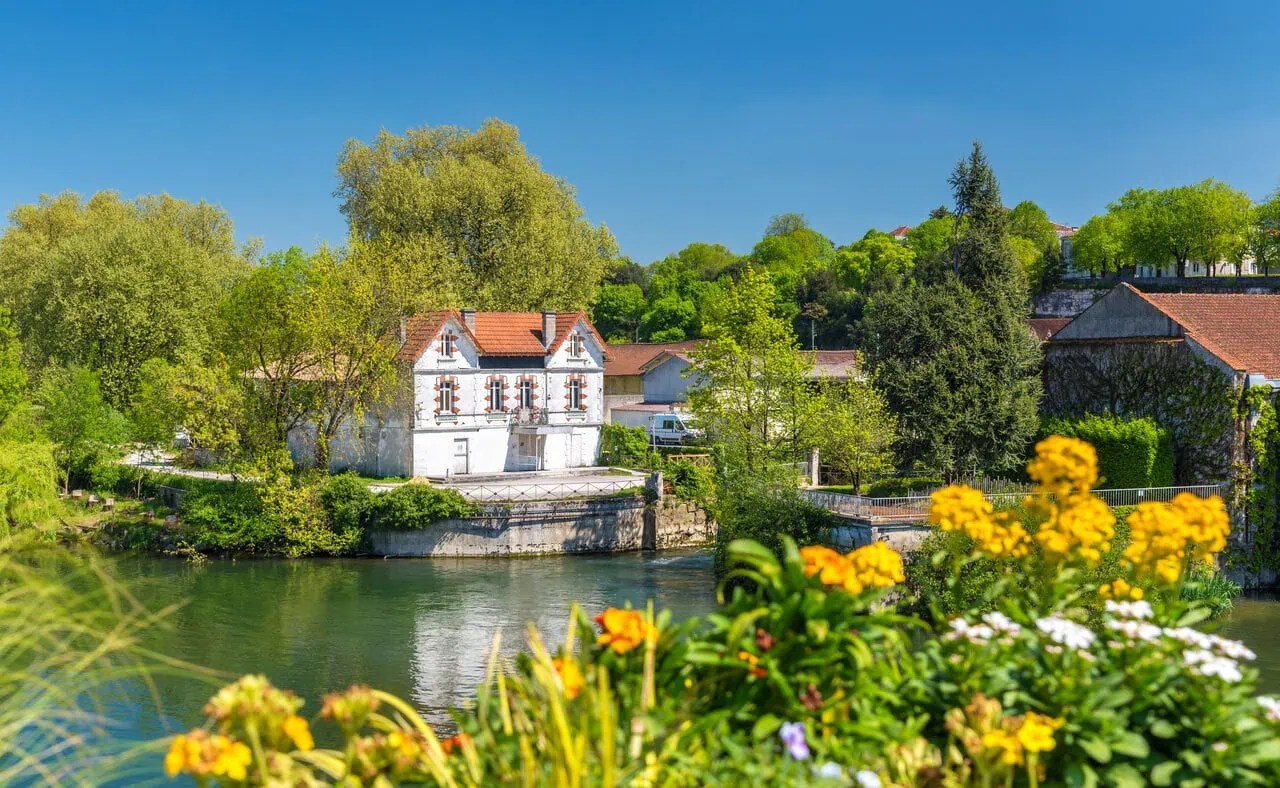 Colourful flowers overlooking the River Charente with traditional houses and riverside scenery in Cognac, France.