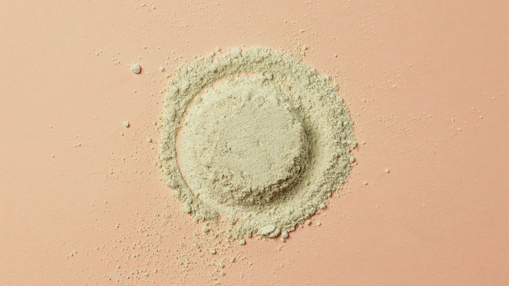 Kaolin, a grainy tan powder, is formed into a circle over a peach colored background.