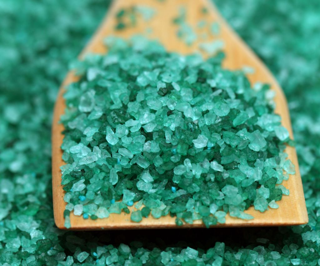 Menthol crystals, mint green, grainy rocks, displayed in a pile on a wooden slate. 