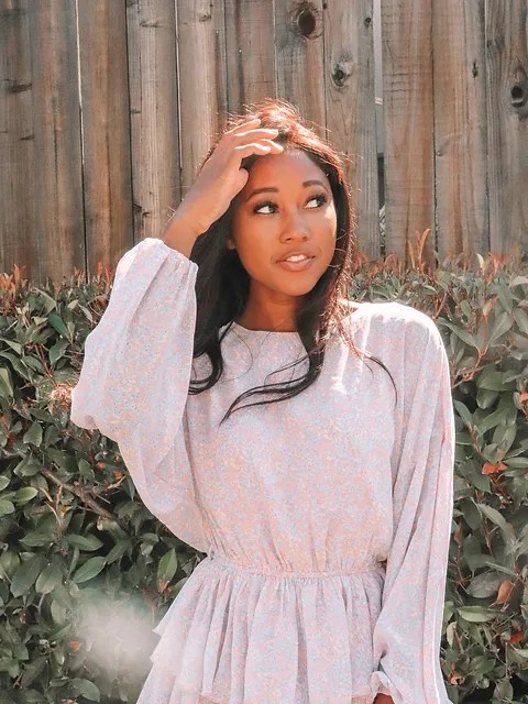 A picture of an African American woman wearing a floral dress and staring off into the distance.