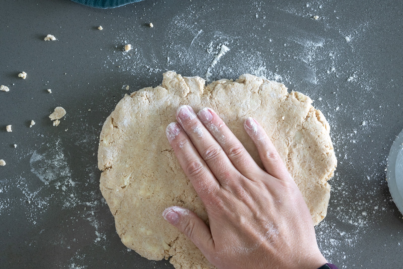 woman pressing biscuit dough on a lightly floured surface.