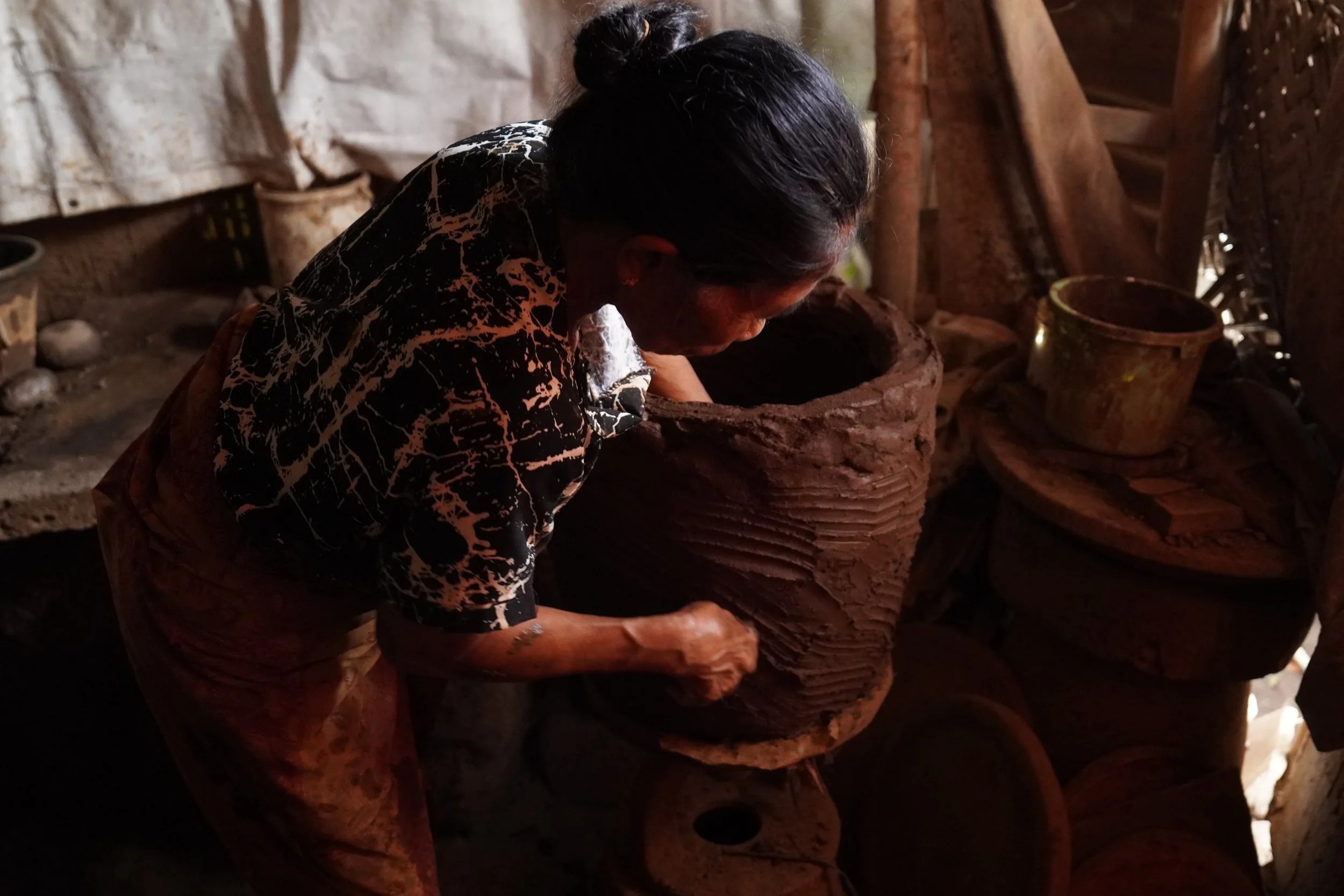 A ceramicist shaping a large clay pot by hand in a traditional workshop