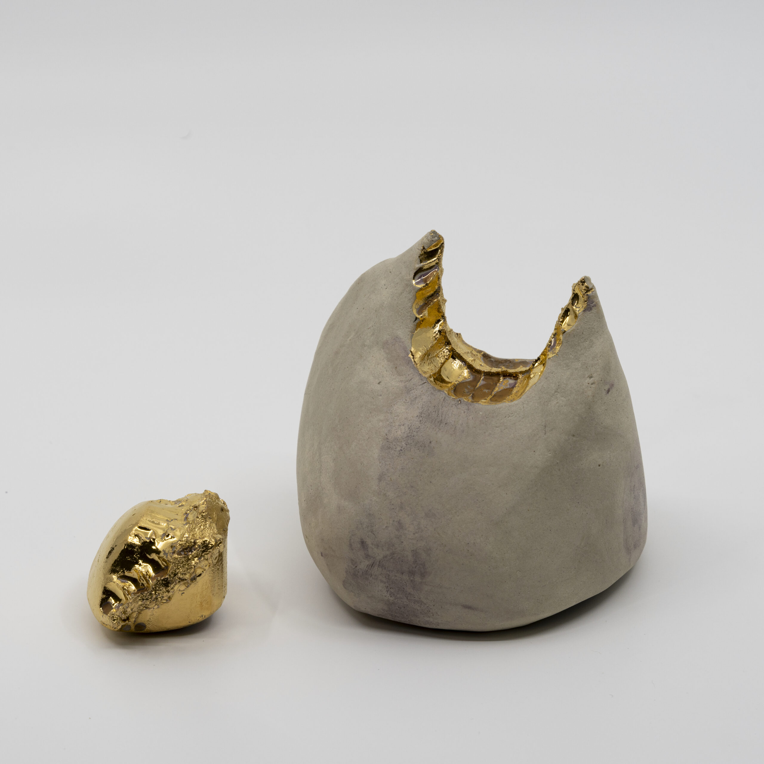 Or 'Midas's Touch' takes its inspiration from the Phrygian king whose golden curse originated across the Aegean from Rhodes, in the mythological landscape of Anatolia. A lump of wedged earthenware holds a single bite: teeth meeting clay in the body's most intimate gesture. The impression is sealed in transparent glaze and 14ct gold lustre; the expelled fragment, equally gilded, lies beside it. Midas could not eat, could not embrace. When touch becomes a transaction, even appetite turns to currency.