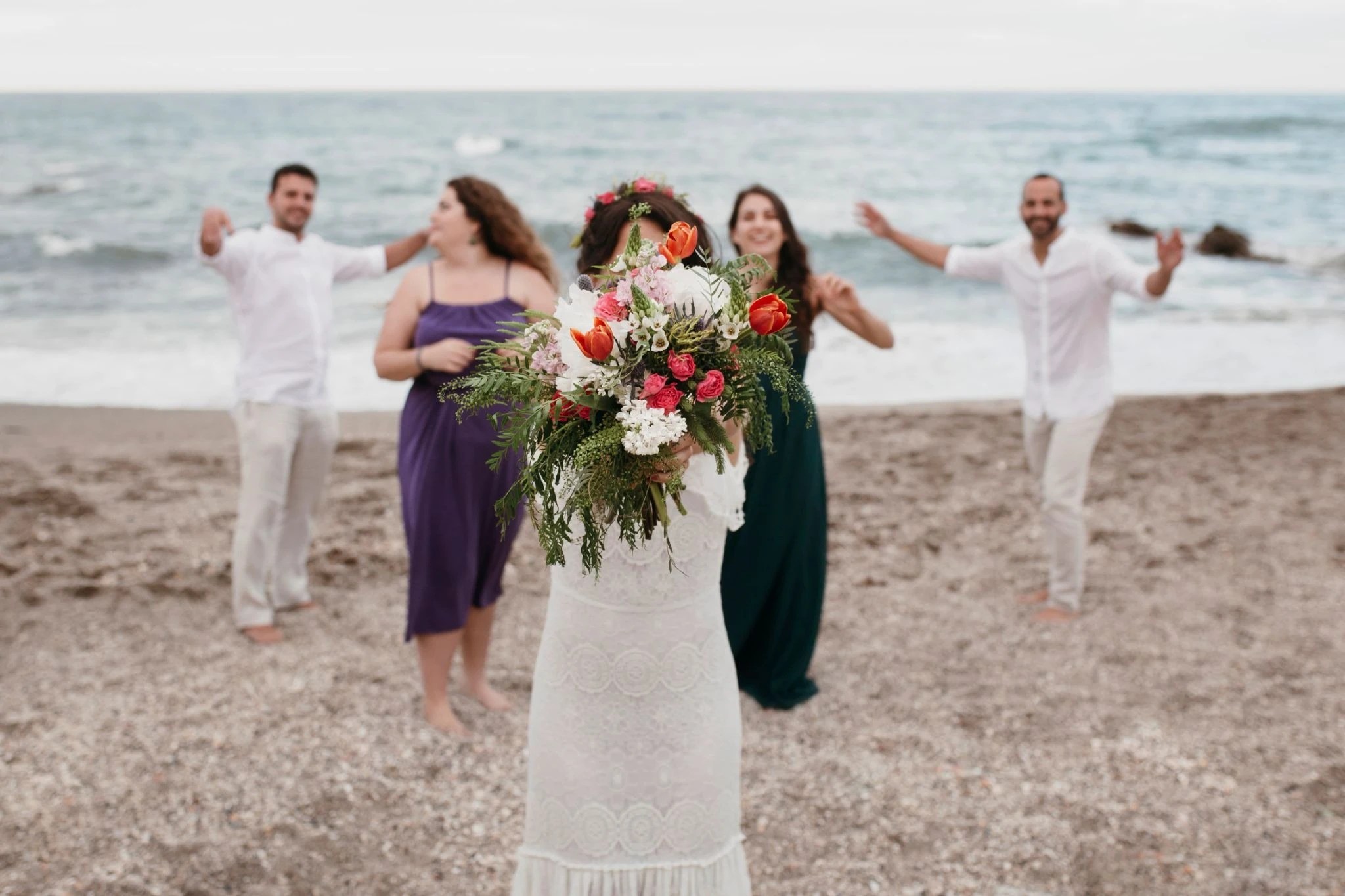 The bride is about to toss her bouquet on the beach.