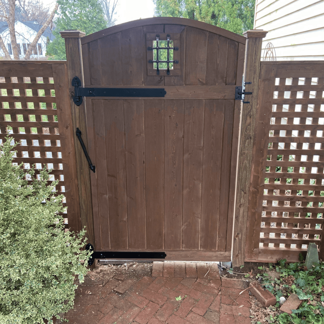 stained wood gate and lattice fence panels with black hardware