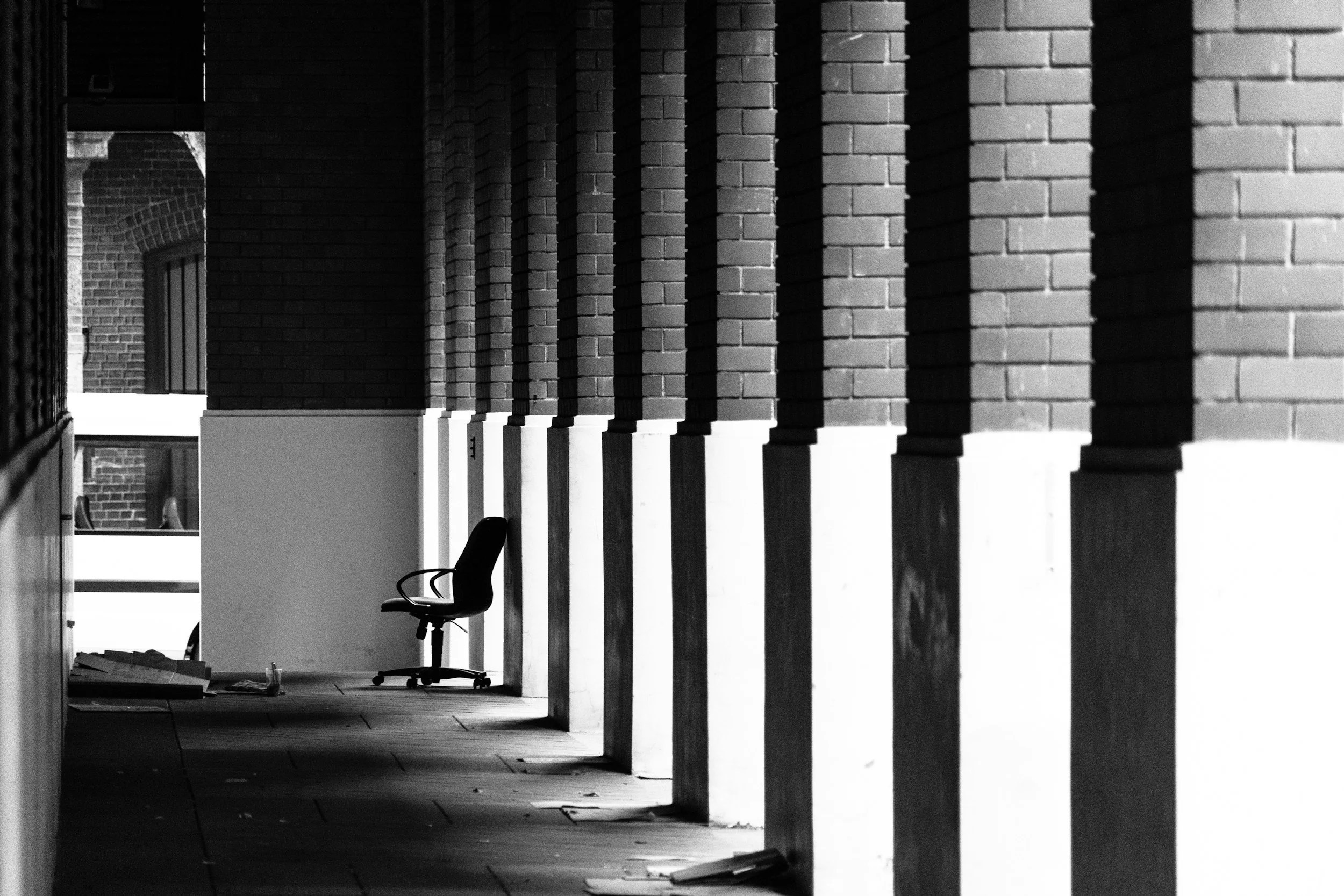 Black and white corridor with brick columns and strong shadows.