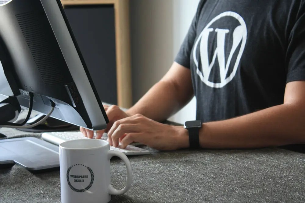 A web designer wears a t-shirt with wordpress logo on it.