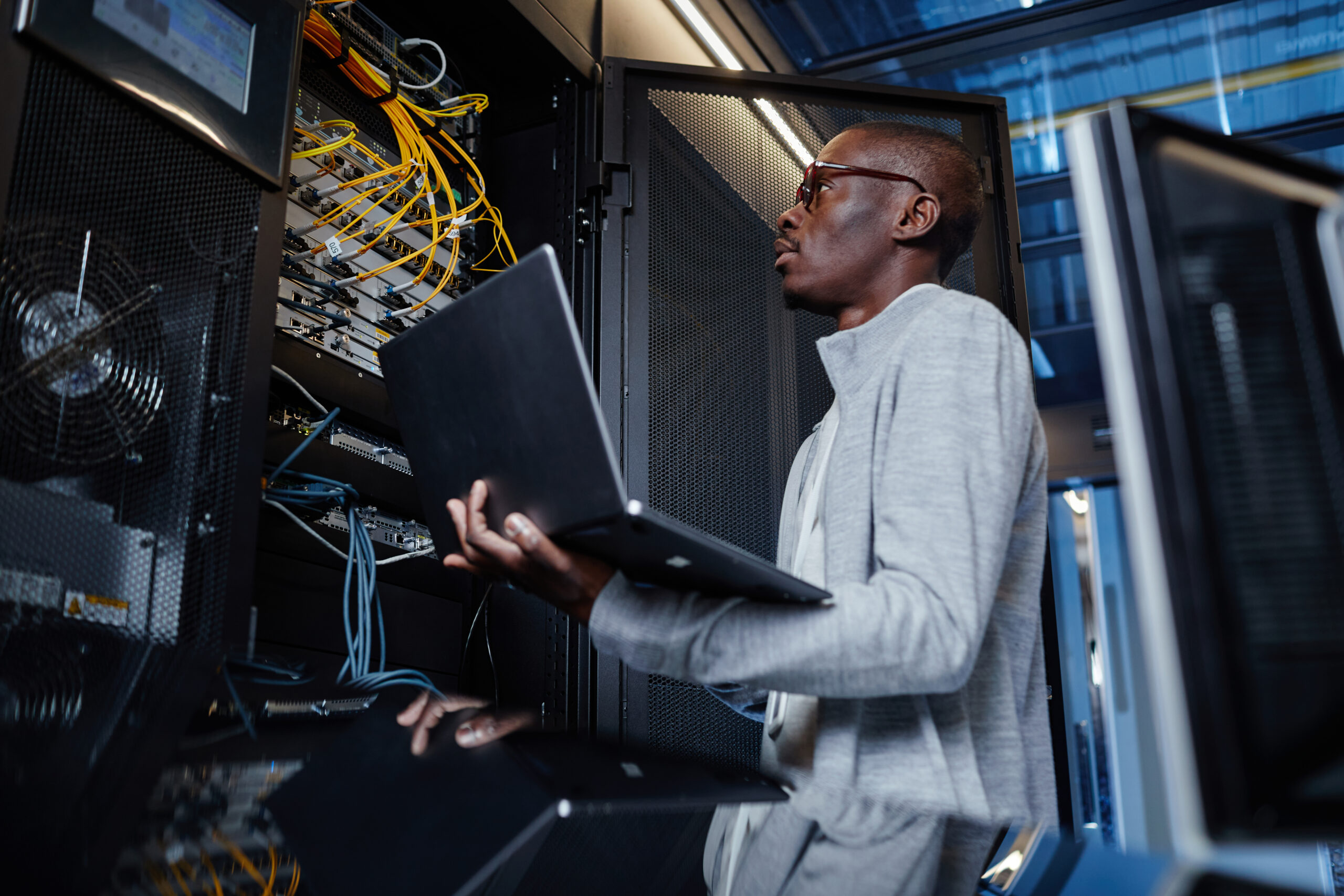 Network Engineer using Laptop in Server Room