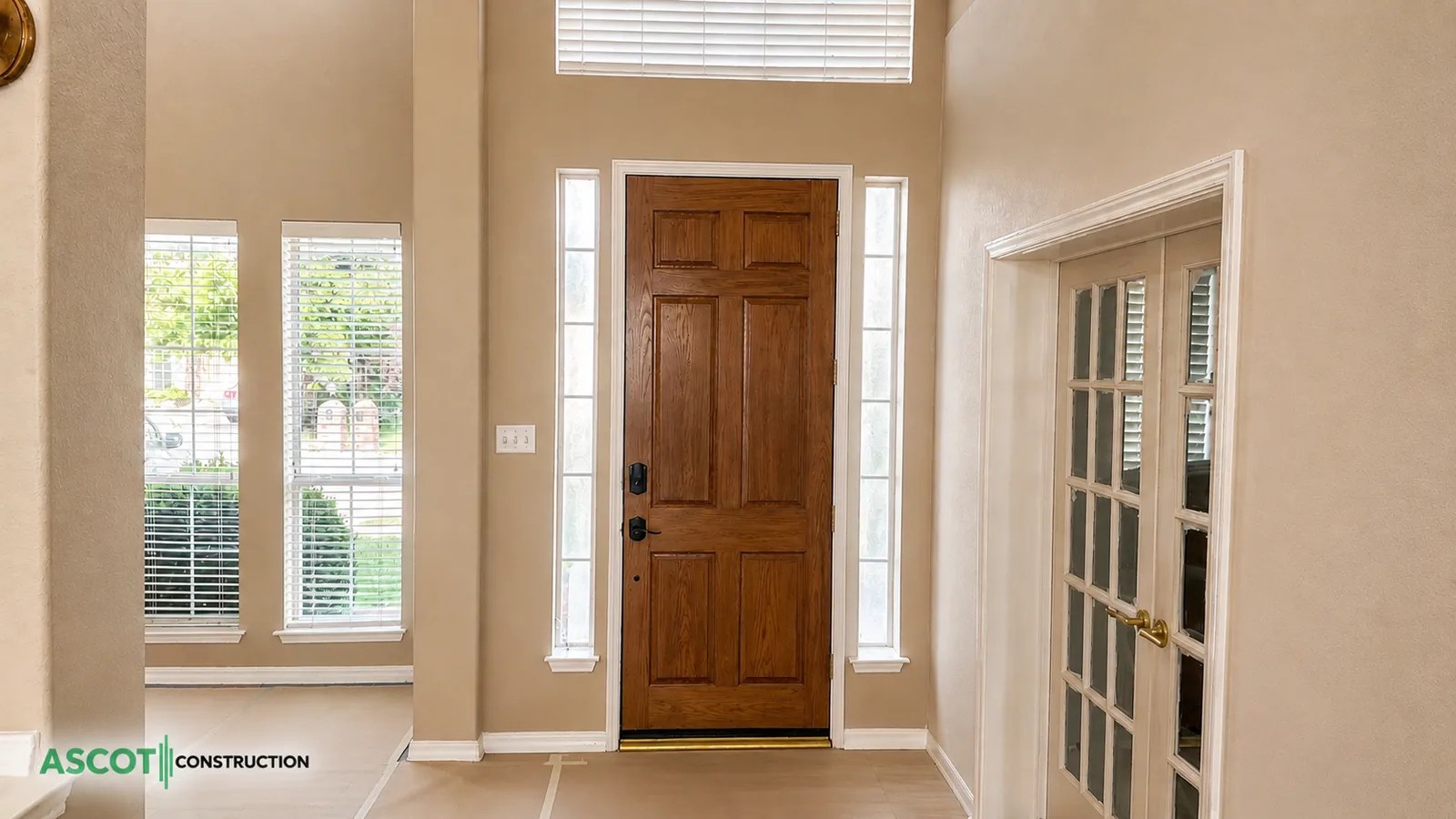 Wood front entry door with glass sidelights and adjacent French doors
