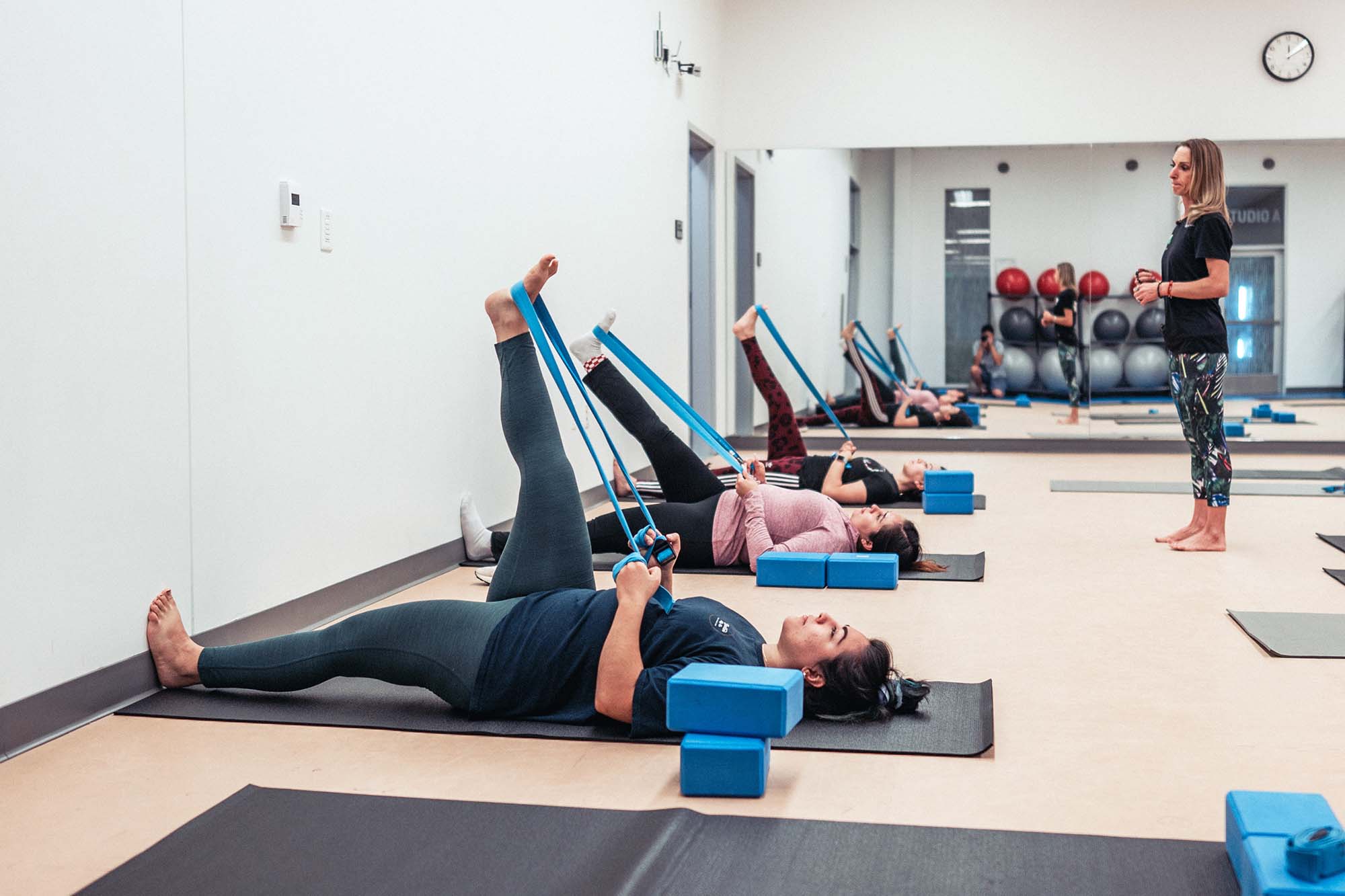 instructor guiding students in yoga stretches