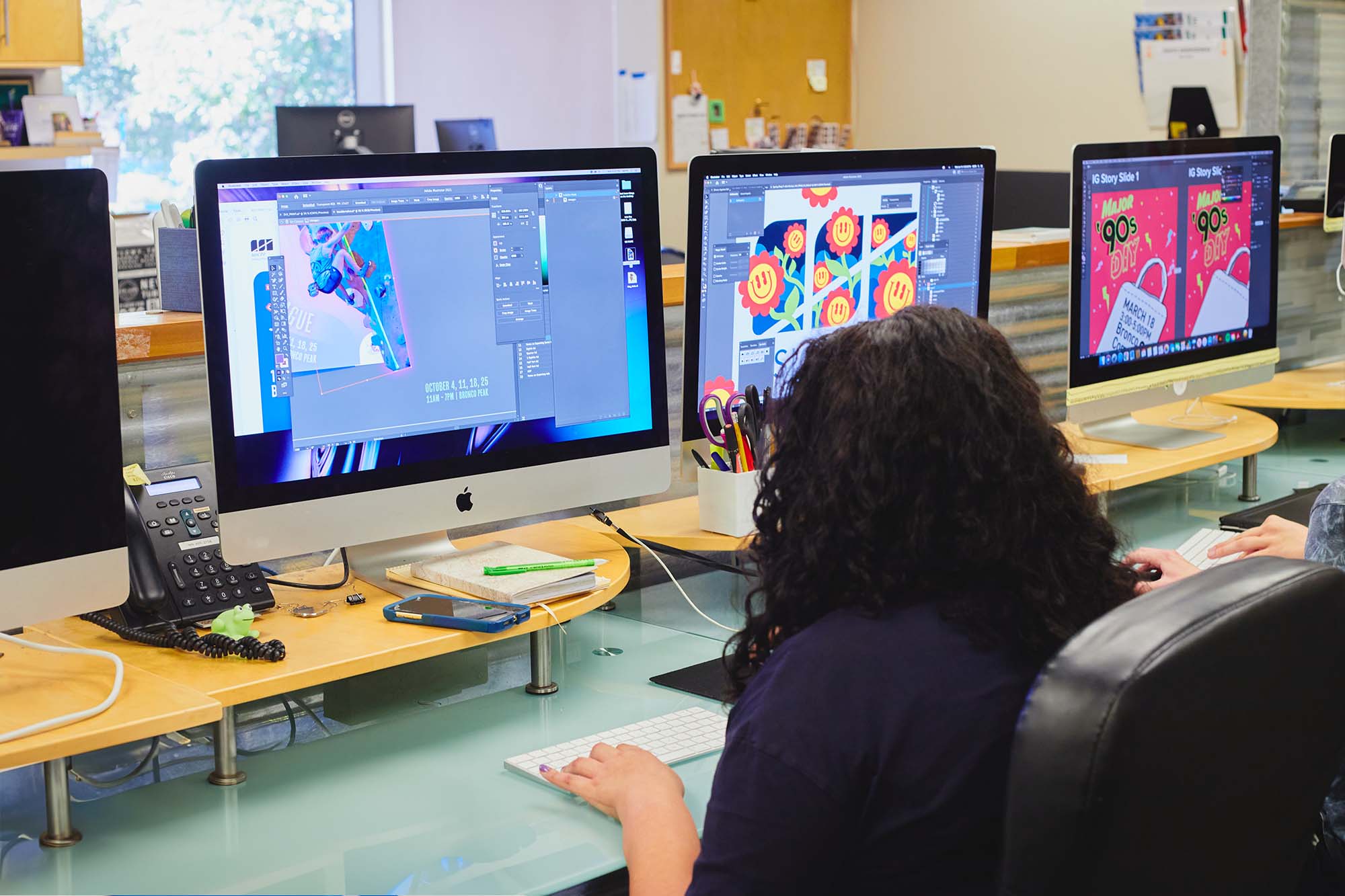 Student working on graphic design projects on a computer in an office