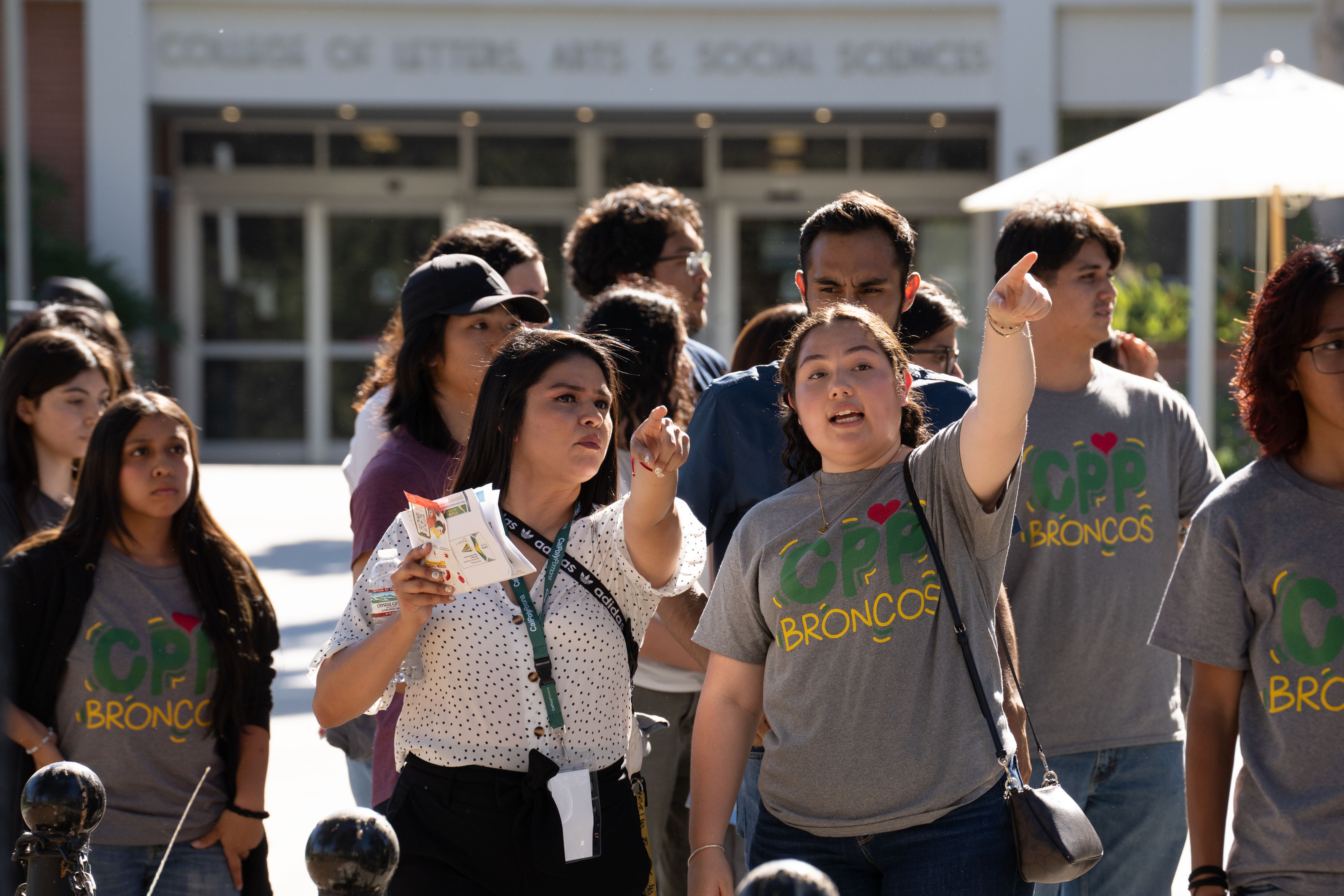 A group of students together with two students pointing in a direction