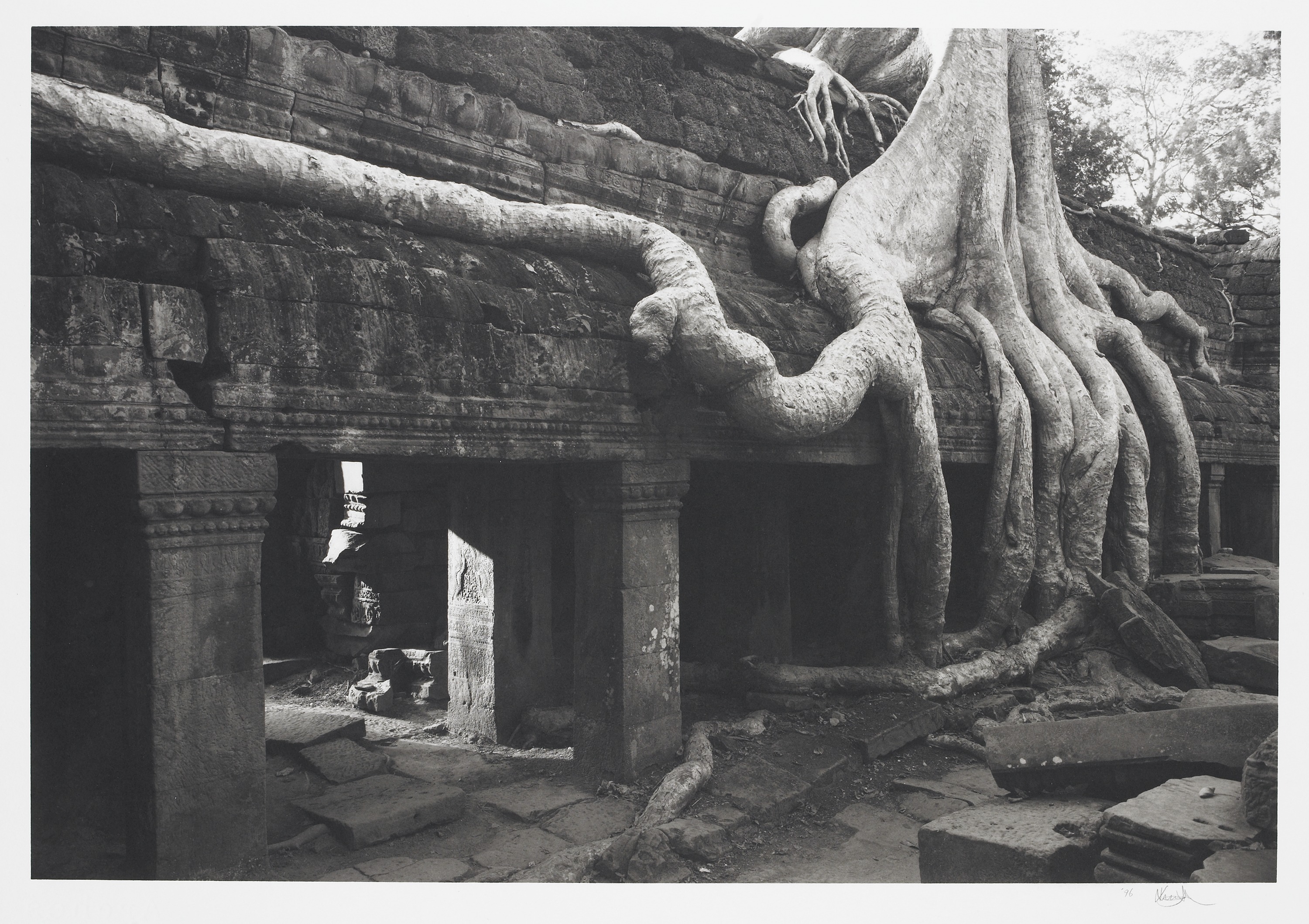 Black and white photo: stone temple at Angkor with roots of a strangler fig crawling over the suface.