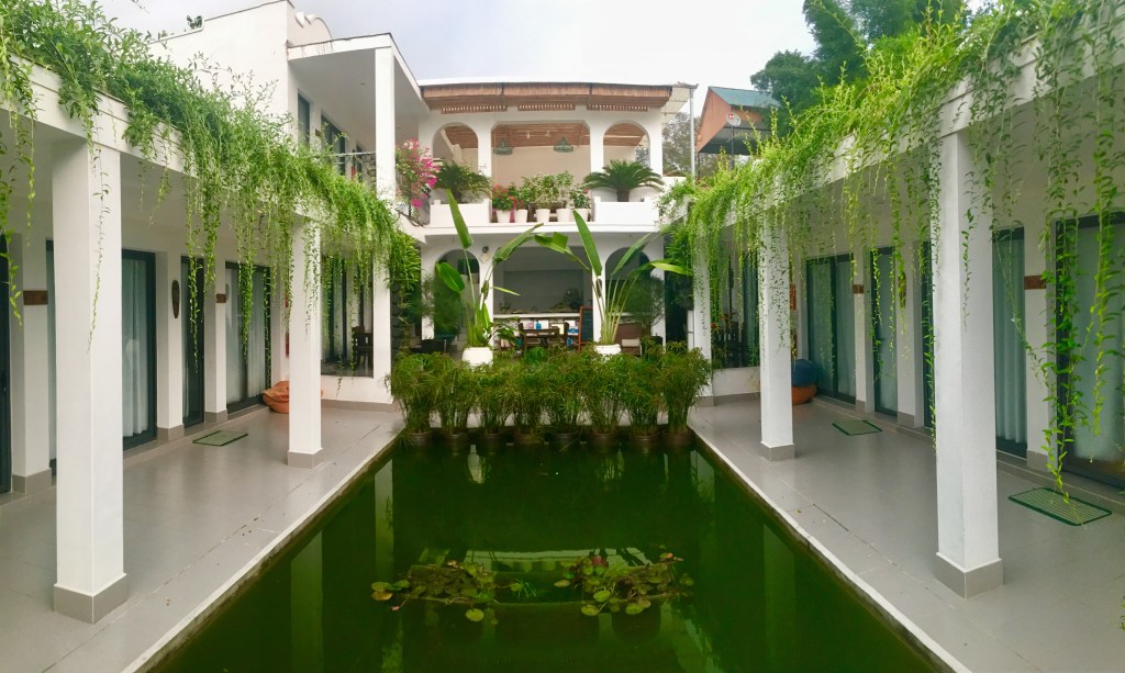 private rooms built around a water feature, with green plants standing out against whitewashed walls at Ca To Eco lodge