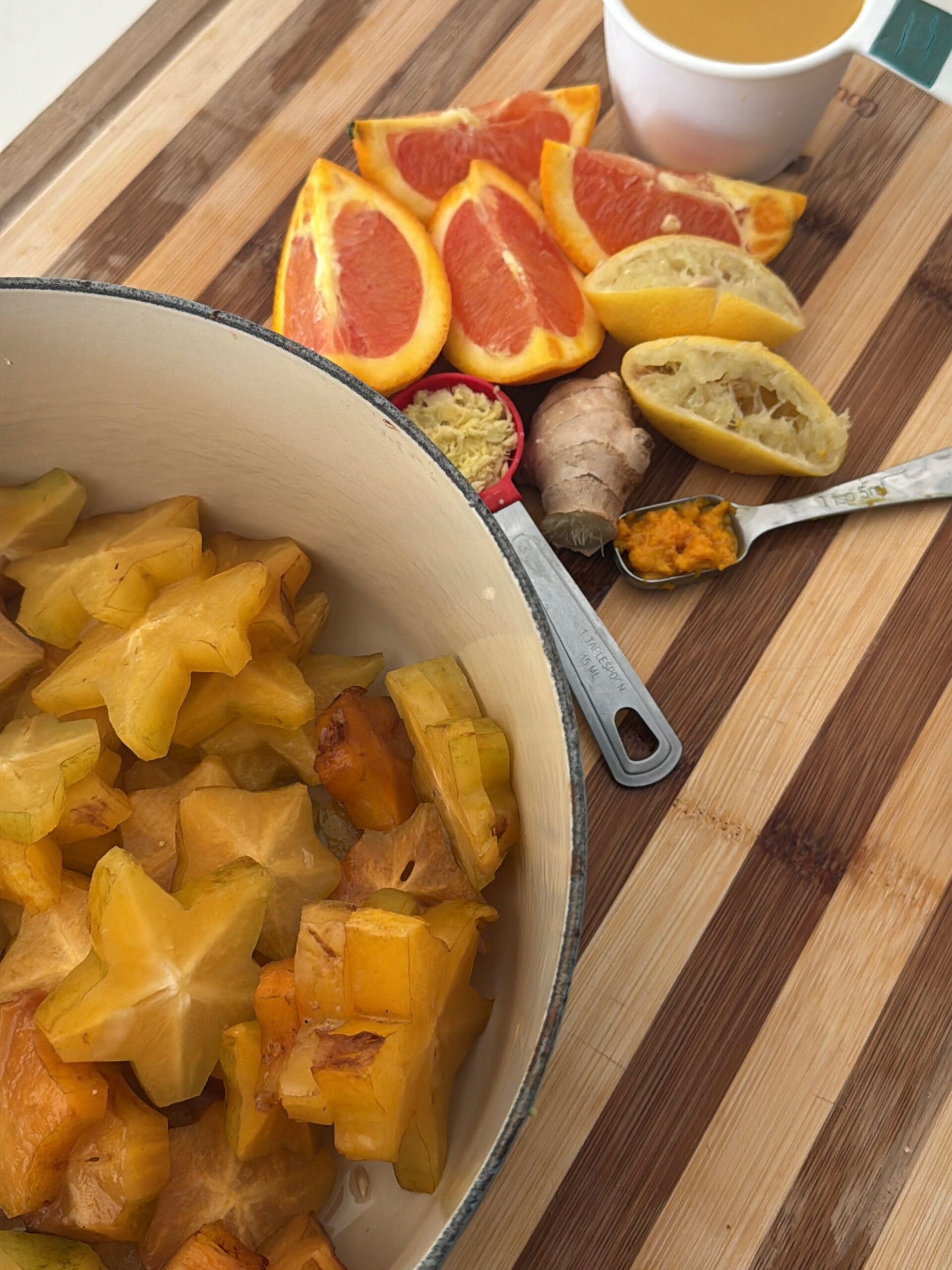 Ingredients for Carambola (starfruit) jam. Sliced starfruit in a dutch oven, orange and lemon slices, teaspoon of orange zest, tablespoon of grated ginger and cup of orange juice.