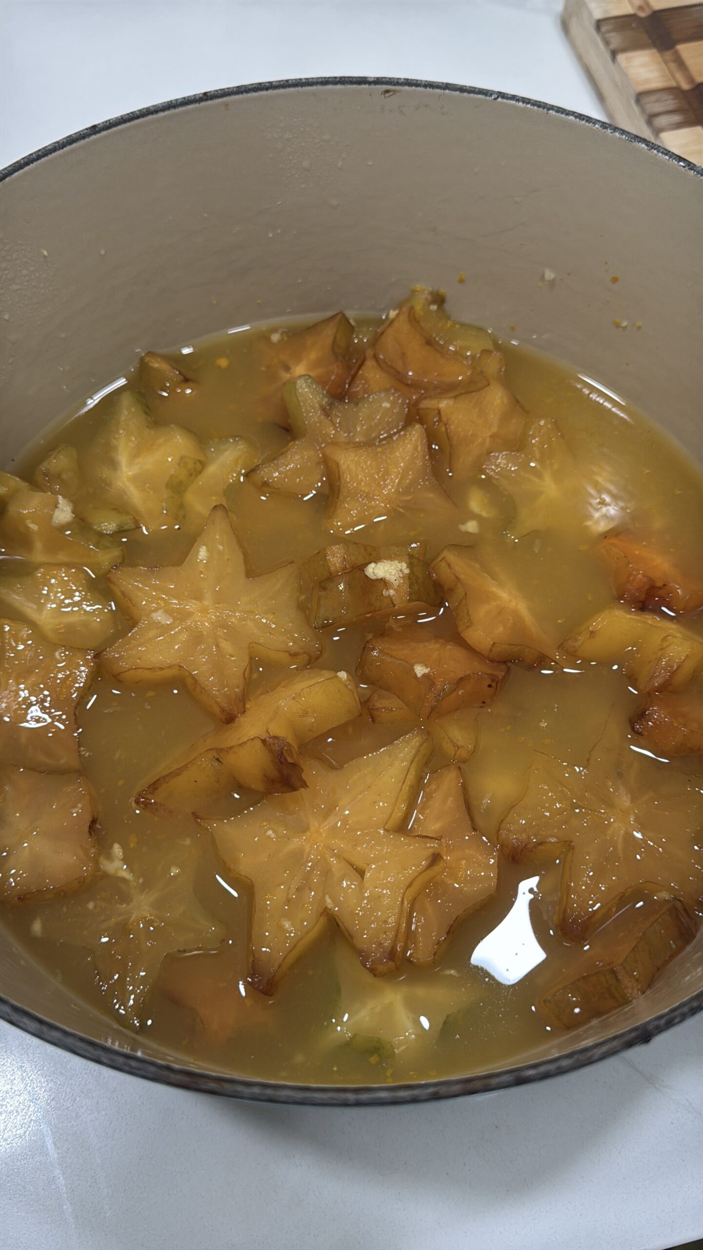 Sliced starfruit in dutch oven with natural juices from sugar