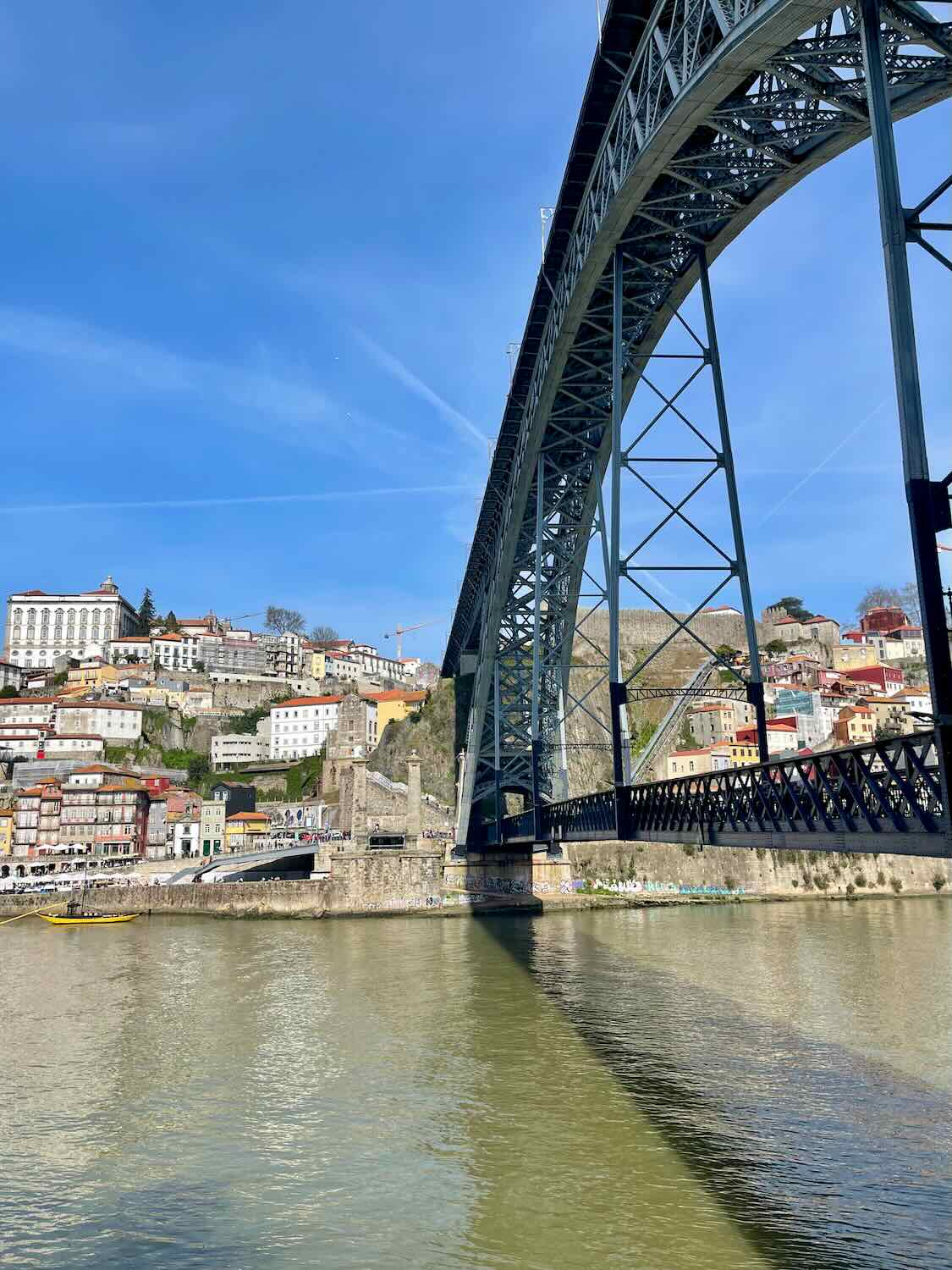 The Dom Lu&iacute;s I Bridge in Porto, spanning over the Douro River with the city's colorful hillside in the background.
